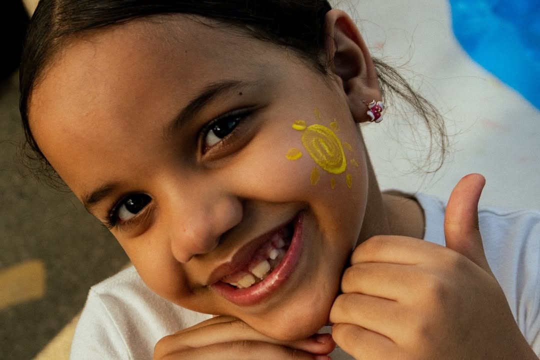 Niña con sol pintado en la mejilla
